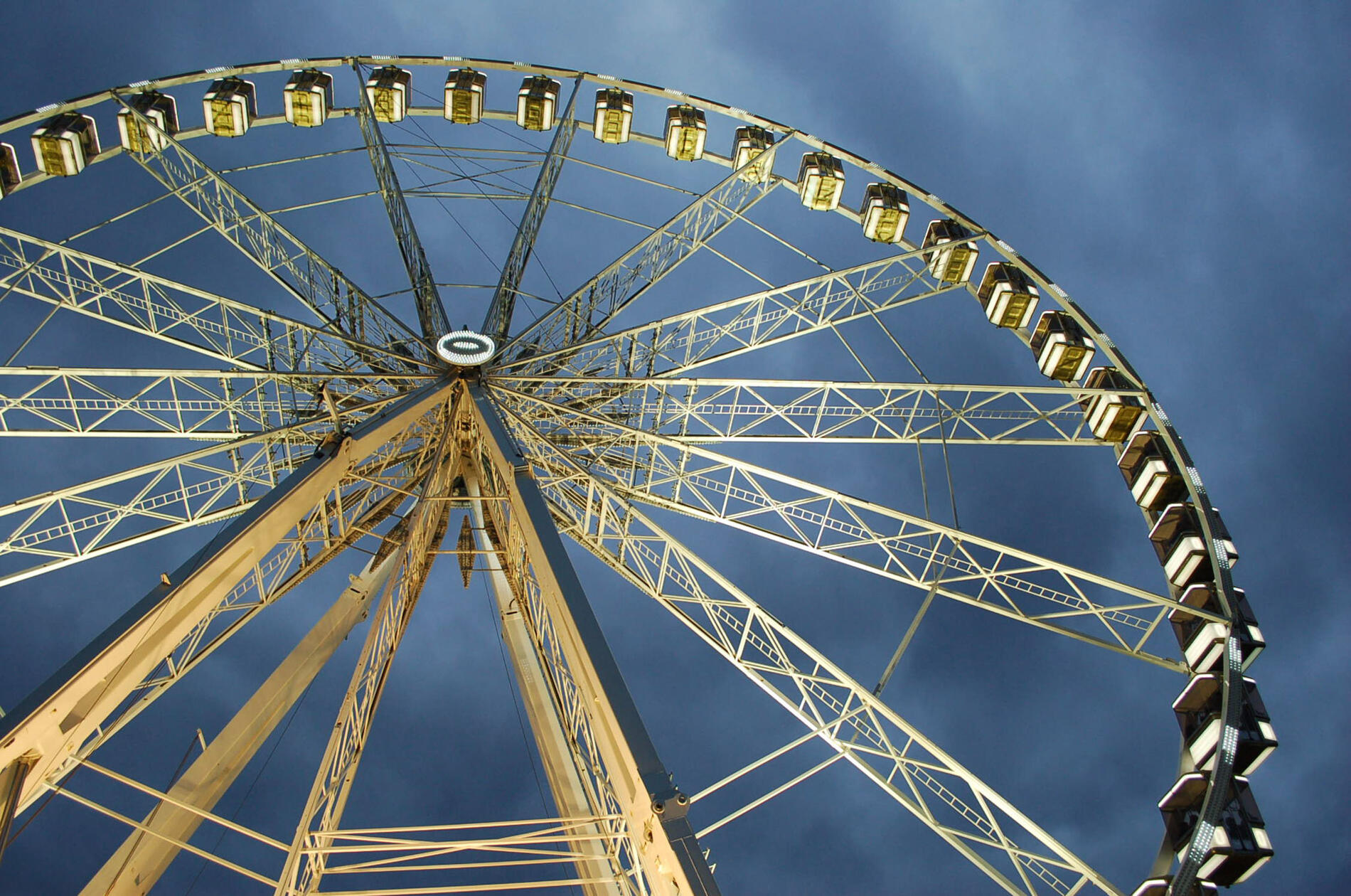 Dramatic Ferris Wheel Photography at Dusk — Illuminated Carnival Ride Against a Stormy Sky